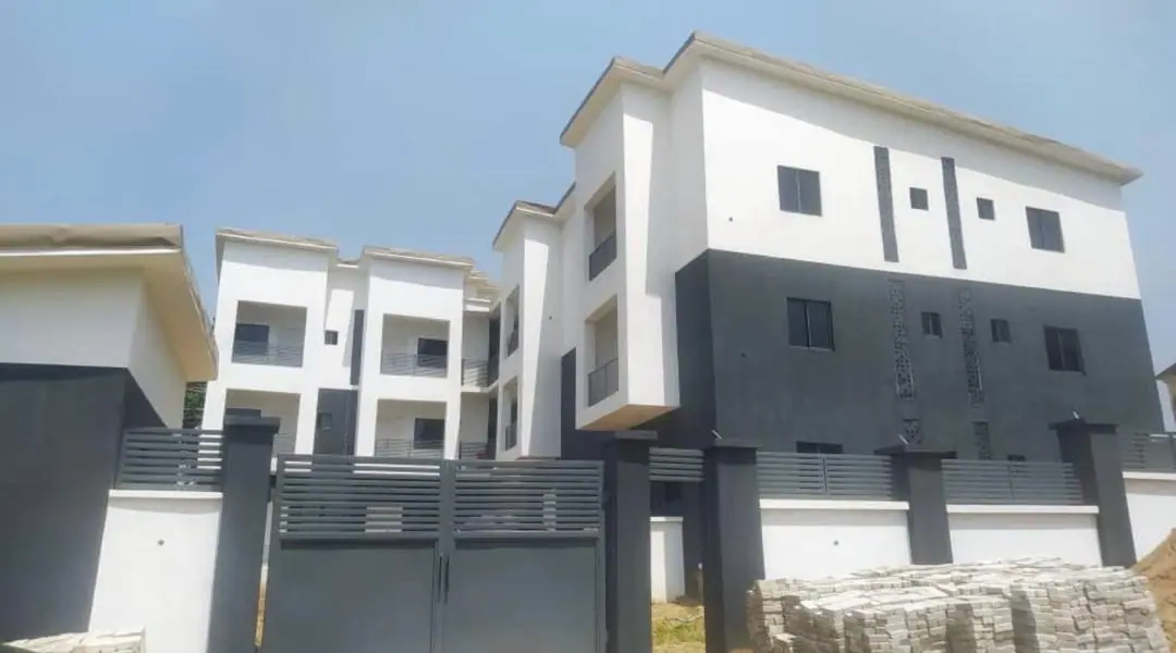 A three-storey white and charcoal residential block behind its charcoal gate