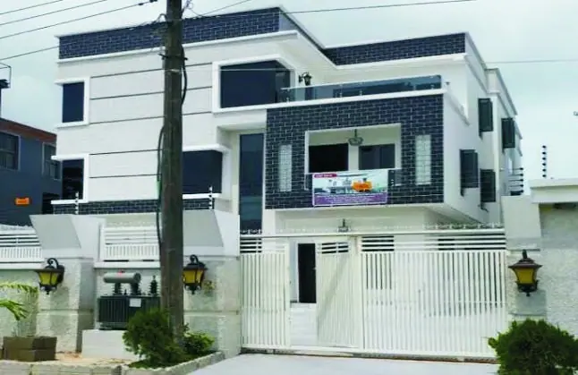 A completed white duplex with charcoal tiled feature walls and a white gate