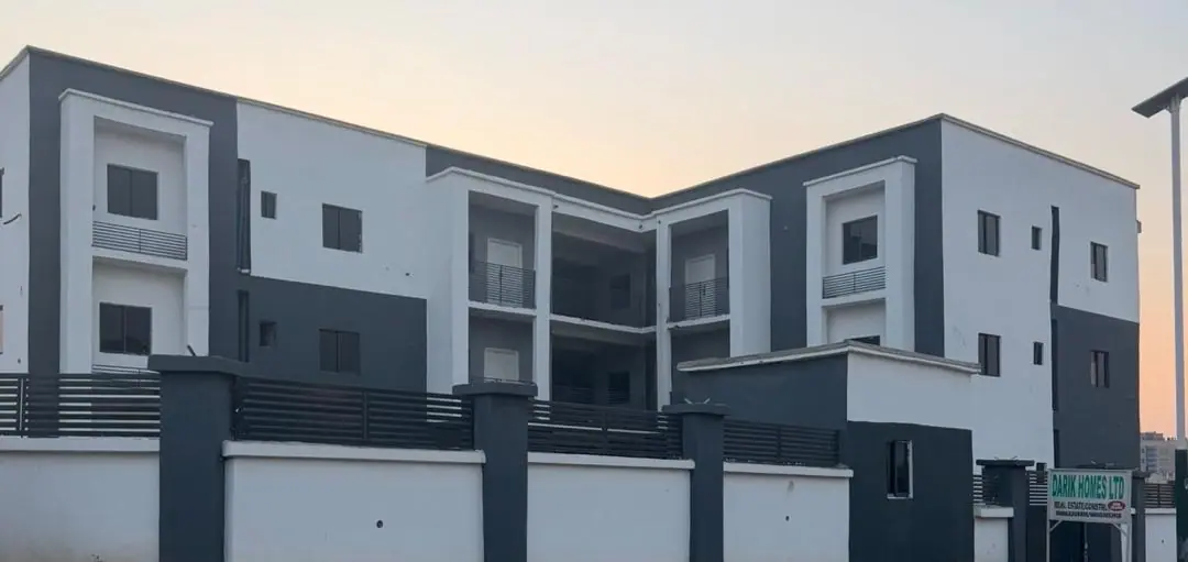 The finished Darik Homes residential block in Kaura District at dusk, seen over its walled frontage