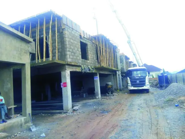 A concrete frame building with formwork and props beside a concrete pump truck